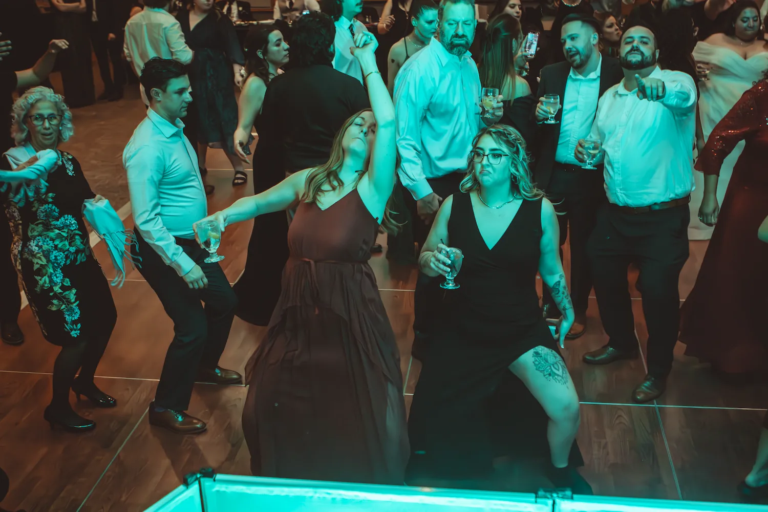 A packed wedding dance floor lit in teal at a Spyder Entertainment reception